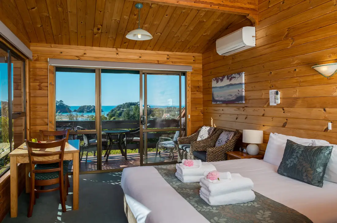 A timber-lined room at Kimi Ora with the bay through the windows.